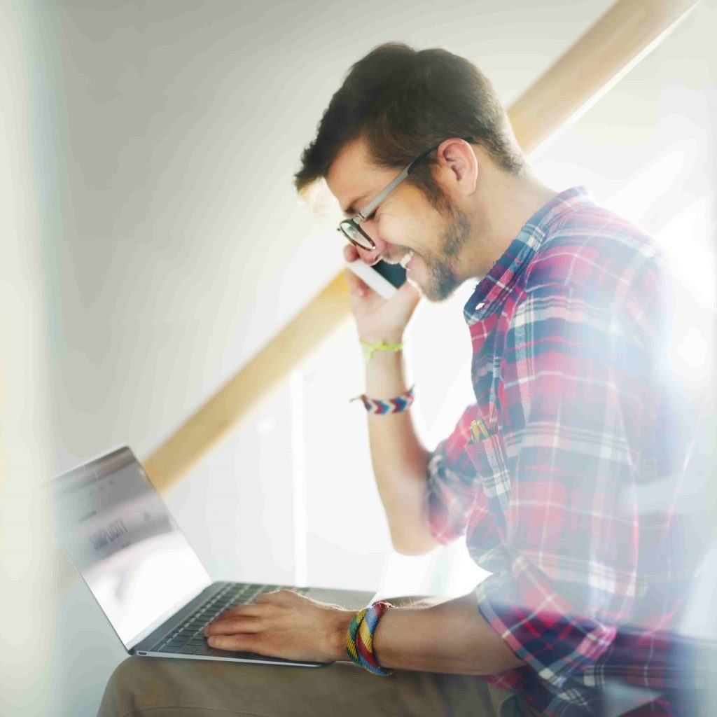 homme au téléphone et devant un ordinateur portable